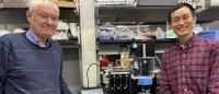 Joachim Frank and Xiangsong Feng stand in front of a counter with research materials behind them.